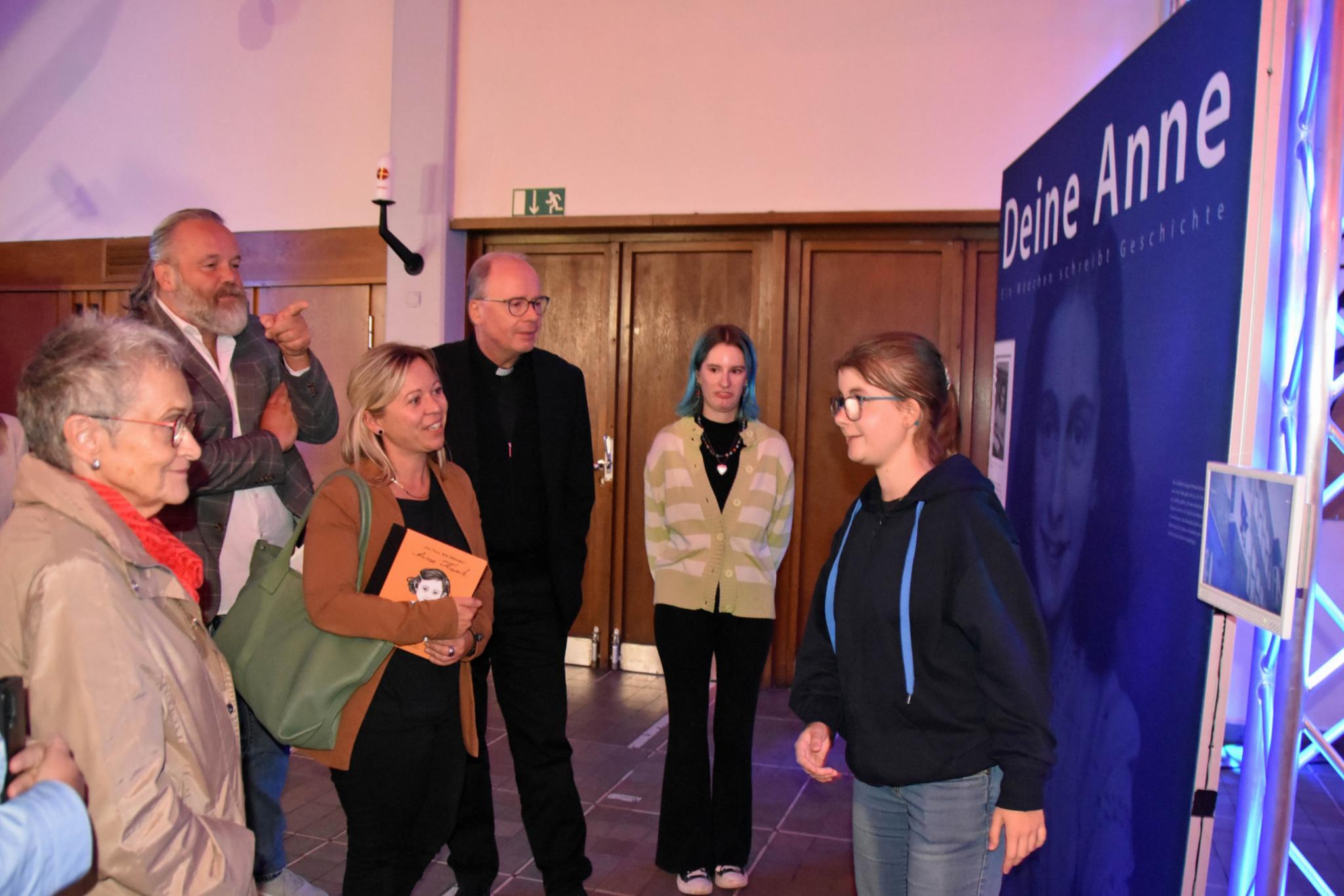 Eine Jugendliche führt Besucher - darunter Staatssekretärin Jessica Heide und Bischof Ackermann - durch die Ausstellung.